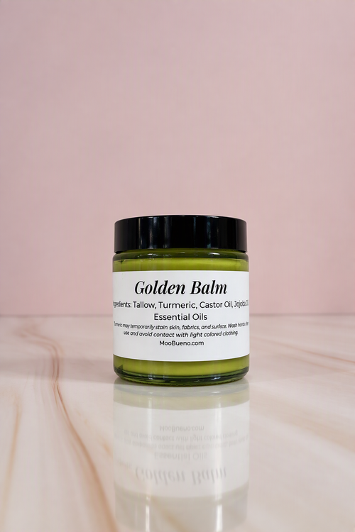 Moo Bueno Skincare Golden Balm, 4 oz glass jar of turmeric tallow body balm on a pink backdrop